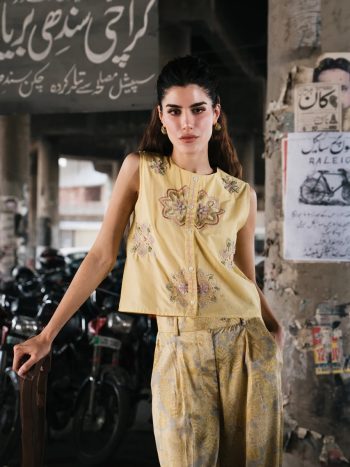 Model wearing sleeveless yellow kurti with floral embroidery